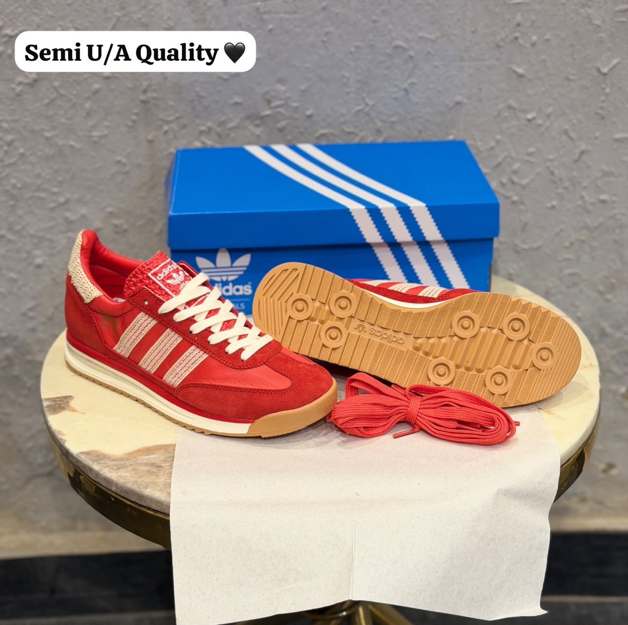 Red low-top retro sneakers with cream-coloured stripes, cream laces, gum-brown outsoles, and an additional pair of red laces