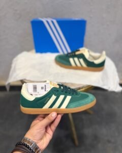 Green retro low-top sneakers with cream stripes, dark green laces, and a gum-colored sole
