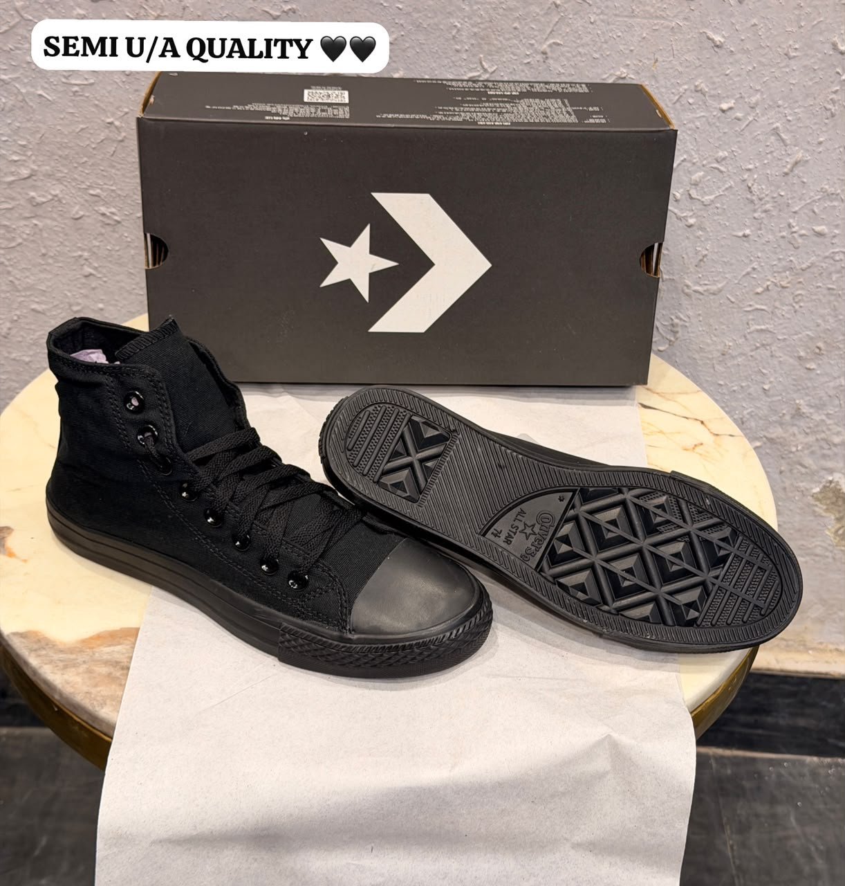 Triple black high top sneakers with a black canvas-style upper, matching laces, dark metal eyelets, textured toe cap, and patterned black outsole