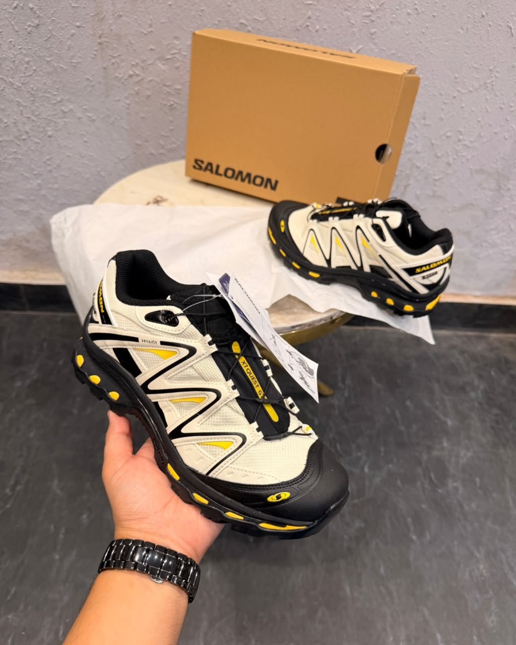 White black and yellow trail-inspired sneakers with layered overlays, chunky black outsole, and deep tread pattern