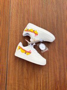 White custom low-top sneakers featuring colourful drip-art graphics in pink, blue, yellow, and purple
