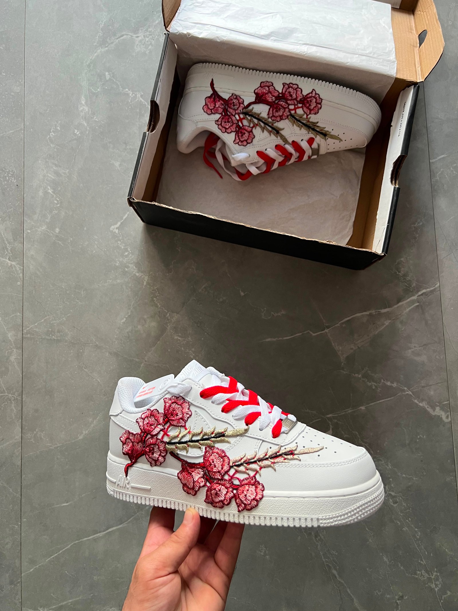White low-top sneakers with raised floral embroidery in red-pink and deep blue colourways