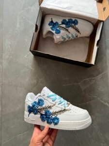 White low-top sneakers with raised floral embroidery in red-pink and deep blue colourways