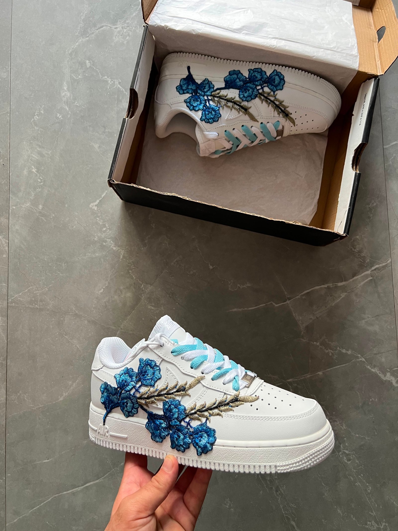 White low-top sneakers with raised floral embroidery in red-pink and deep blue colourways