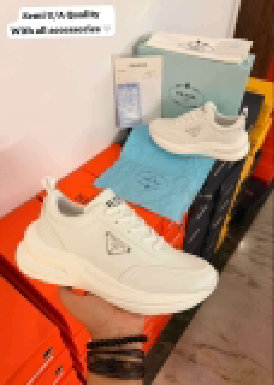 White minimalist low-top sneakers with a sculpted chunky sole, tonal panels, lace-up closure, and decorative side emblem