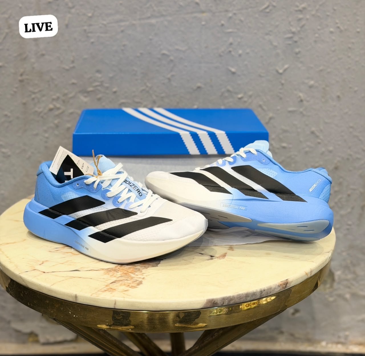 White and sky blue athletic-style sneakers with black side stripes, lace-up closure, and a sculpted white and blue sole