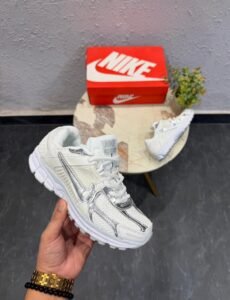 White sneakers with metallic silver swoosh detailing, layered panels, and chunky white soles