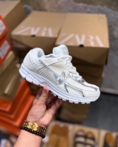 White sneakers with metallic silver swoosh detailing, layered panels, and chunky white soles