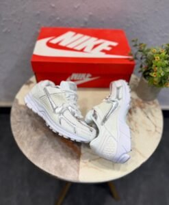 White sneakers with metallic silver swoosh detailing, layered panels, and chunky white soles