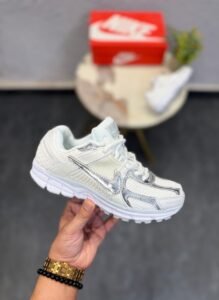 White sneakers with metallic silver swoosh detailing, layered panels, and chunky white soles